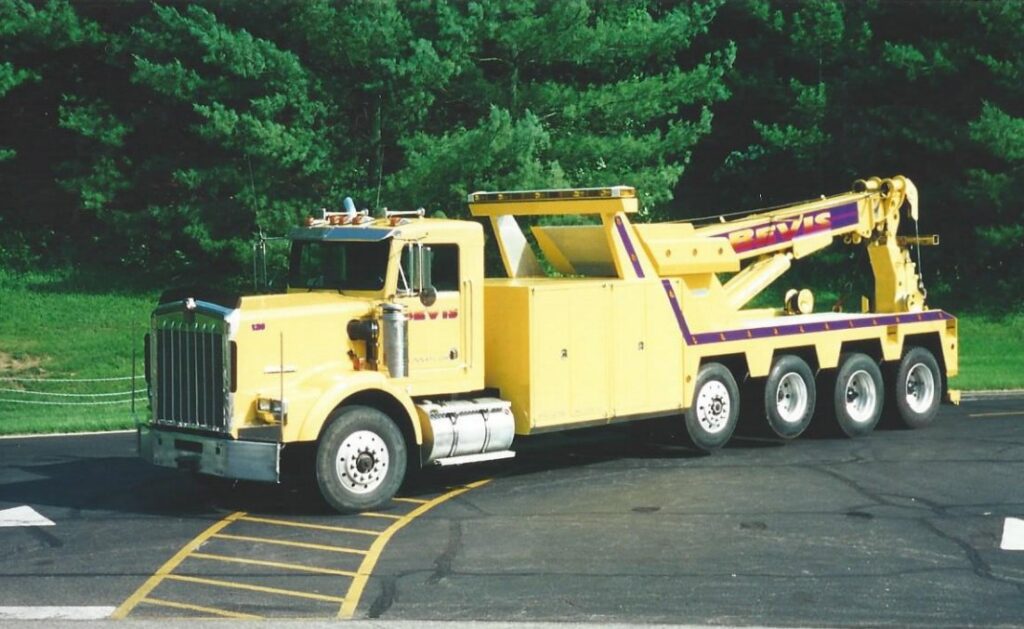 A Bevis Towing heavy-duty tow truck with a red boom lifting a flatbed trailer in Cincinnati, OH.