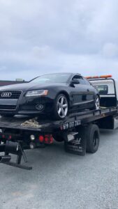 A black Audi coupe being transported on a flatbed tow truck by Cali kings Towing in San Diego, CA.