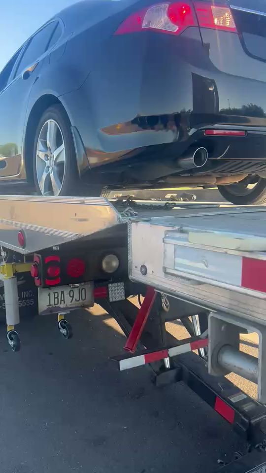 A black car being loaded onto a flatbed tow truck by Poly's Towing Glendale, AZ.