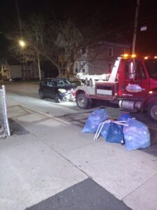 A black car being towed by a RonniesTowing&Recovery truck at night in Bryan, TX