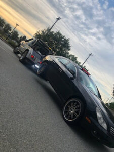 A black car being towed by a J & G Towing, LLC truck at sunset in Greensboro, NC.