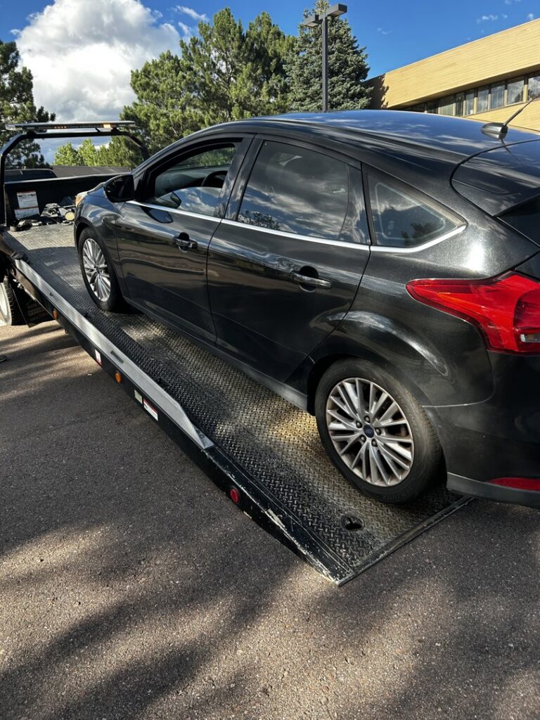 A black car loaded onto a flatbed tow truck by Towing Colorado in Colorado Springs, CO.