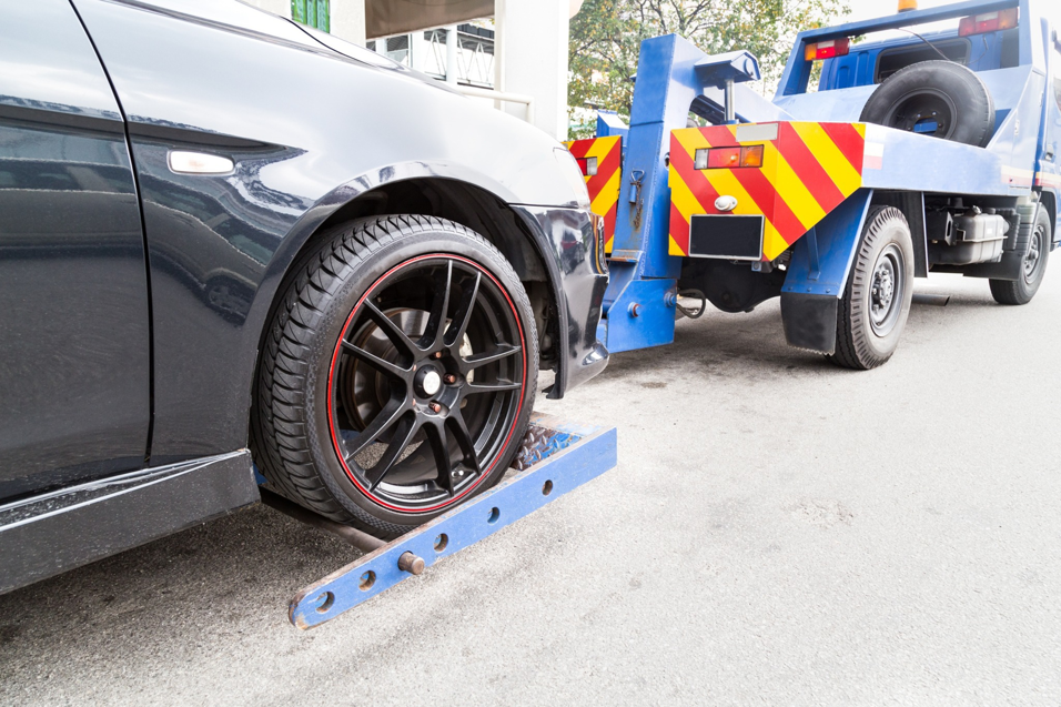 A black car being carefully loaded onto a flatbed tow truck by Buckeye Riverside Towing in Cincinnati, OH.