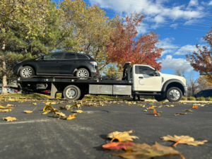 A black car being towed on a flatbed truck by Cities Superior Towing Corp. in Lake Charles, LA, during autumn.