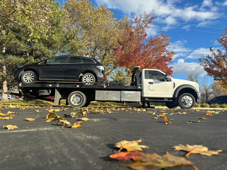 A black car being towed on a flatbed truck by Cities Superior Towing Corp. in Lake Charles, LA, during autumn.