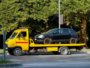 A black car being transported on a yellow flatbed tow truck by DunRite Towing Jonesboro in Jonesboro, AR.
