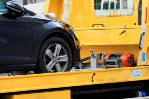 A black car being loaded onto a yellow flatbed tow truck by Towing Las Vegas Nevada in Las Vegas, NV.