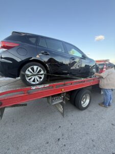 A black car securely loaded onto a flatbed tow truck by 918 Wrecker Service in Tulsa, OK.