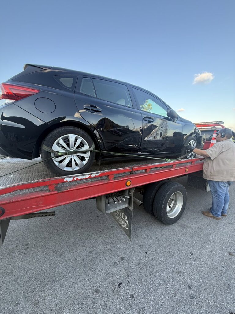 A black car securely loaded onto a flatbed tow truck by 918 Wrecker Service in Tulsa, OK.