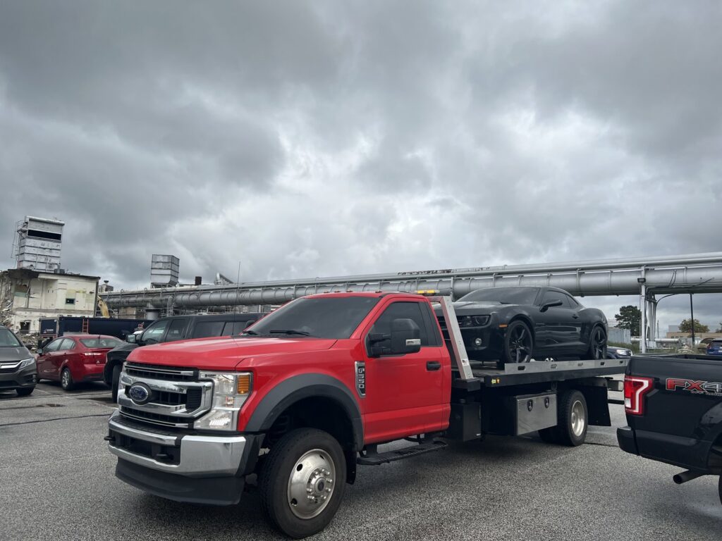 A black Chevrolet Camaro being transported on a flatbed tow truck by Quiñones Towing in Cleveland, OH.