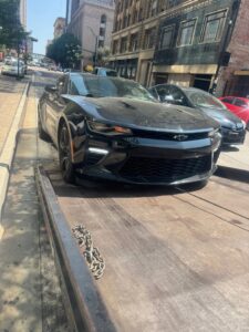 A black Chevrolet Camaro being towed on a flatbed tow truck by Black Rhino Towing in Denver, CO.