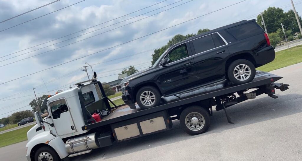 A black Chevy Tahoe SUV loaded onto a flatbed tow truck from Wilkerson's Towing & Automotive LLC in Bowling Green, KY.