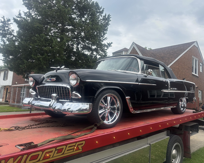 A black classic car, a Chevrolet Bel Air, secured on a flatbed tow truck by Triple D's Towing in Sterling Heights, MI.