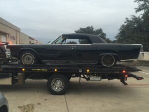 A black classic convertible car being transported on a Tow Jam flatbed tow truck in Dallas, TX.