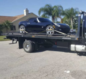 A black convertible car securely loaded onto a flatbed tow truck by Bakersfield Towing Company in Bakersfield, CA.
