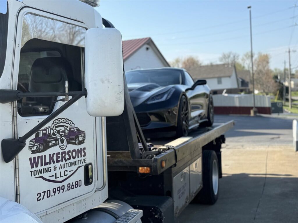 A black Corvette sports car loaded onto a flatbed tow truck from Wilkerson's Towing & Automotive LLC in Bowling Green, KY.