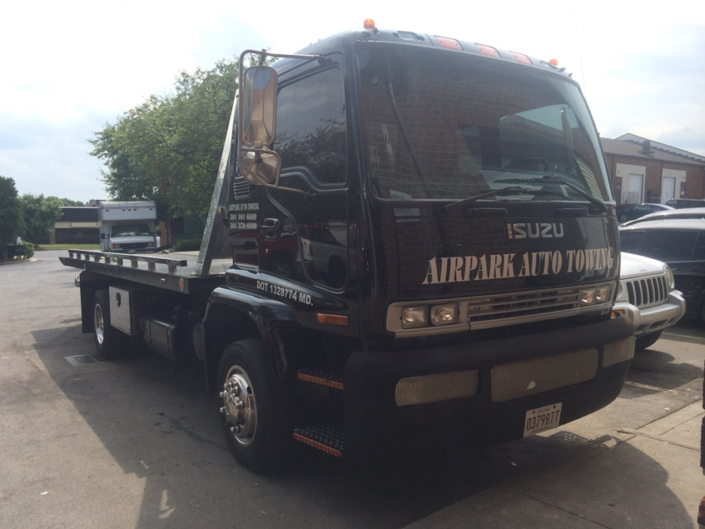 A black flatbed tow truck from Airpark Auto Center, ready for towing services in Gaithersburg, MD.