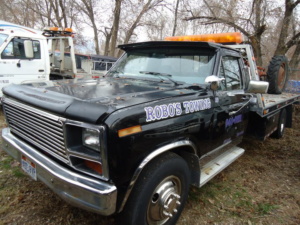 A black flatbed tow truck with Robo's Towing branding in Marriott-Slaterville, UT, ready for service.