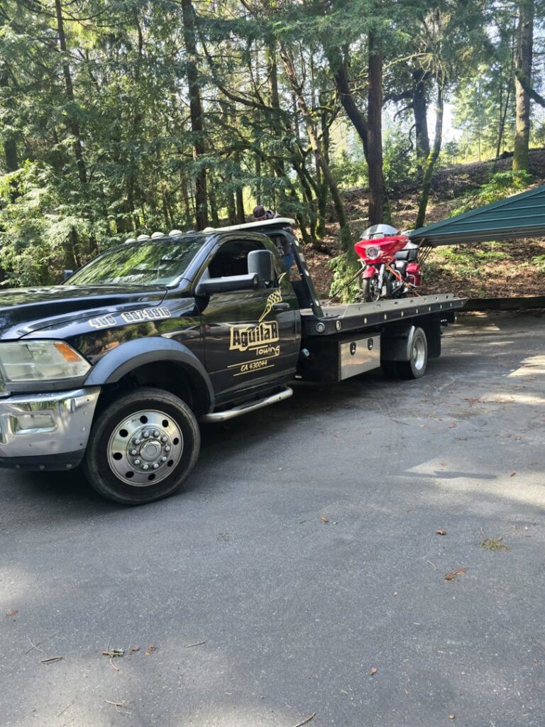Aguilar Towing's black flatbed tow truck transporting a red motorcycle in San Jose, CA