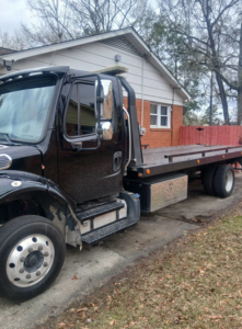 A black flatbed tow truck parked, ready for service, from Towing services in North Charleston, SC.