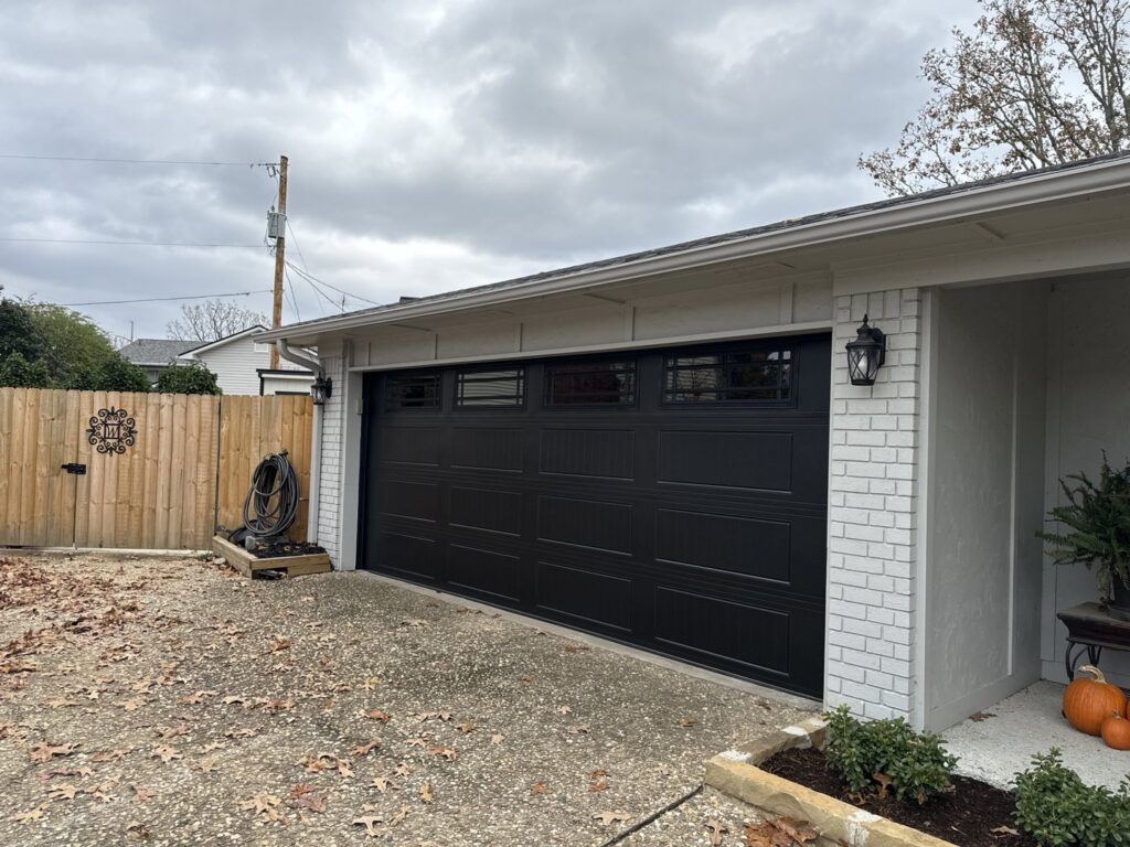 A newly installed black garage door on a brick home by LaFrancis Overhead Door LLC in Little Rock, AR