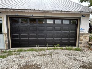 A modern black garage door with windows installed on a new construction home by Woodwards Overhead Door Co. in Topeka, KS
