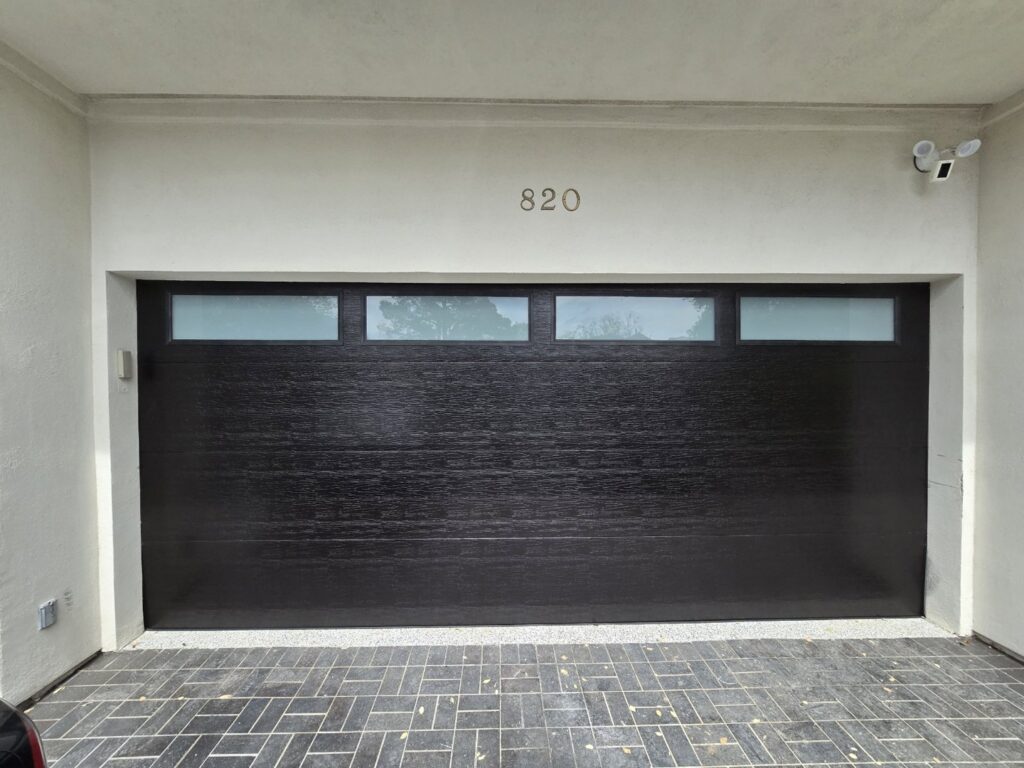 A black garage door with horizontal windows at the top installed by Giddy Up Garage Doors & Iron in Las Vegas, NV.