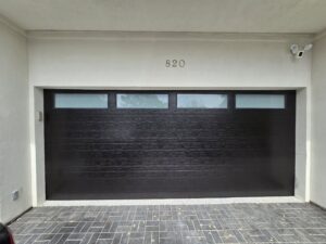 A black garage door with horizontal windows at the top installed by Giddy Up Garage Doors & Iron in Las Vegas, NV.