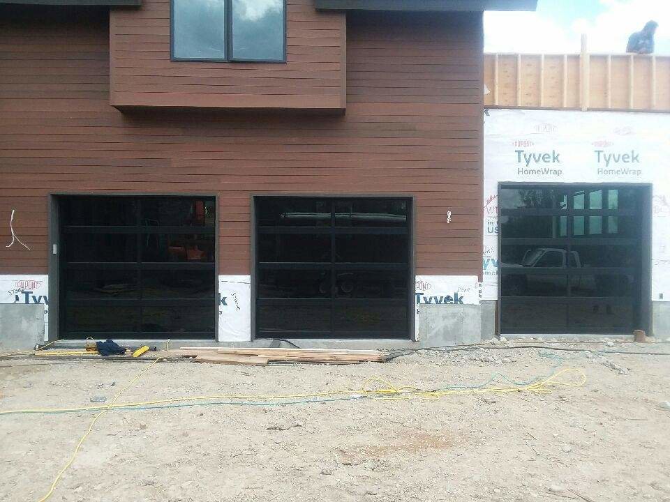 Three black glass garage doors installed on a building under construction by Riverside Garage Doors in Kalispell, MT.