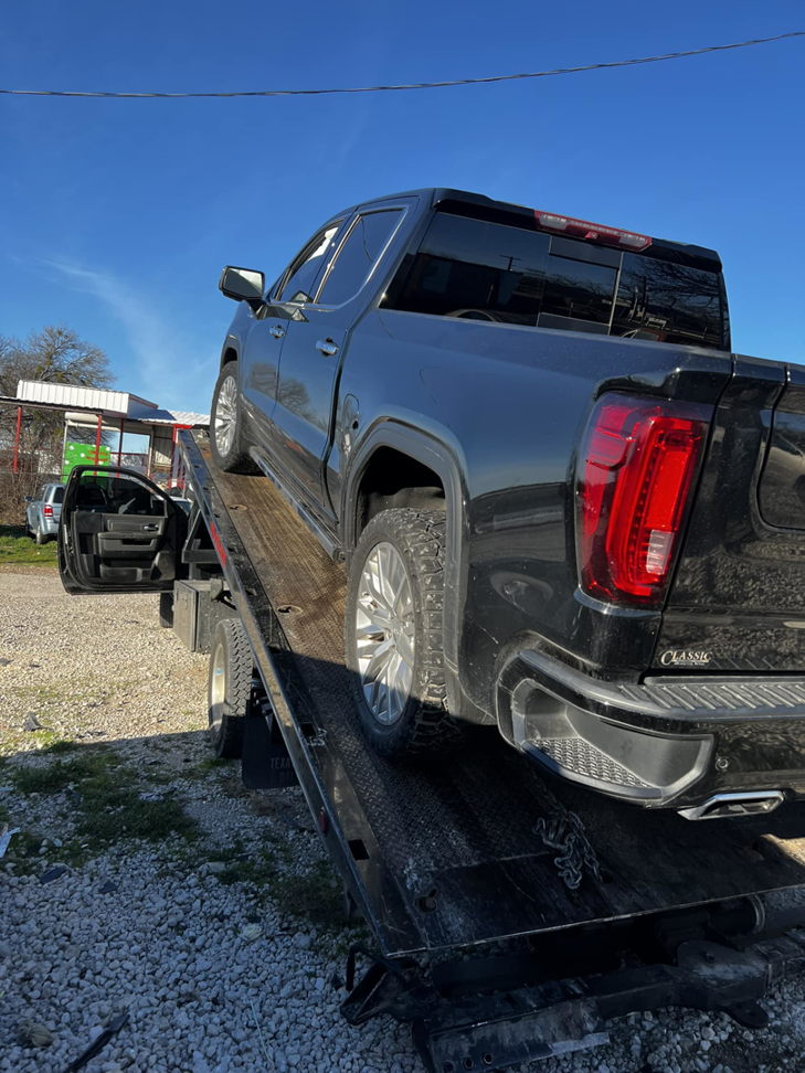A black GMC Sierra pickup truck being loaded onto a flatbed tow truck by Heavy Hookz Towing in Fort Worth, TX.