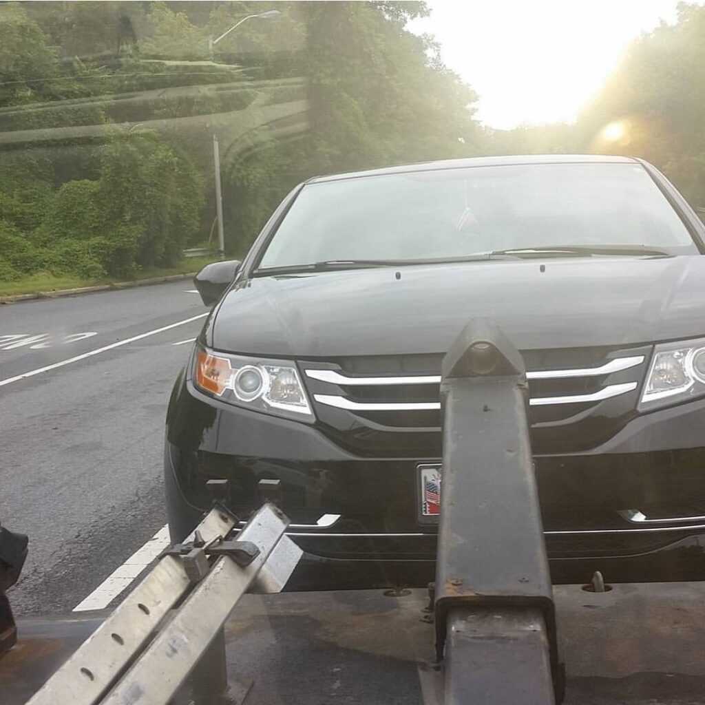 A black Honda Odyssey minivan being towed by Whitelock Towing in Baltimore, MD.