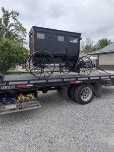 A black horse-drawn buggy being transported on a flatbed tow truck by First Hand Towing & Recovery in Fort Wayne, IN.