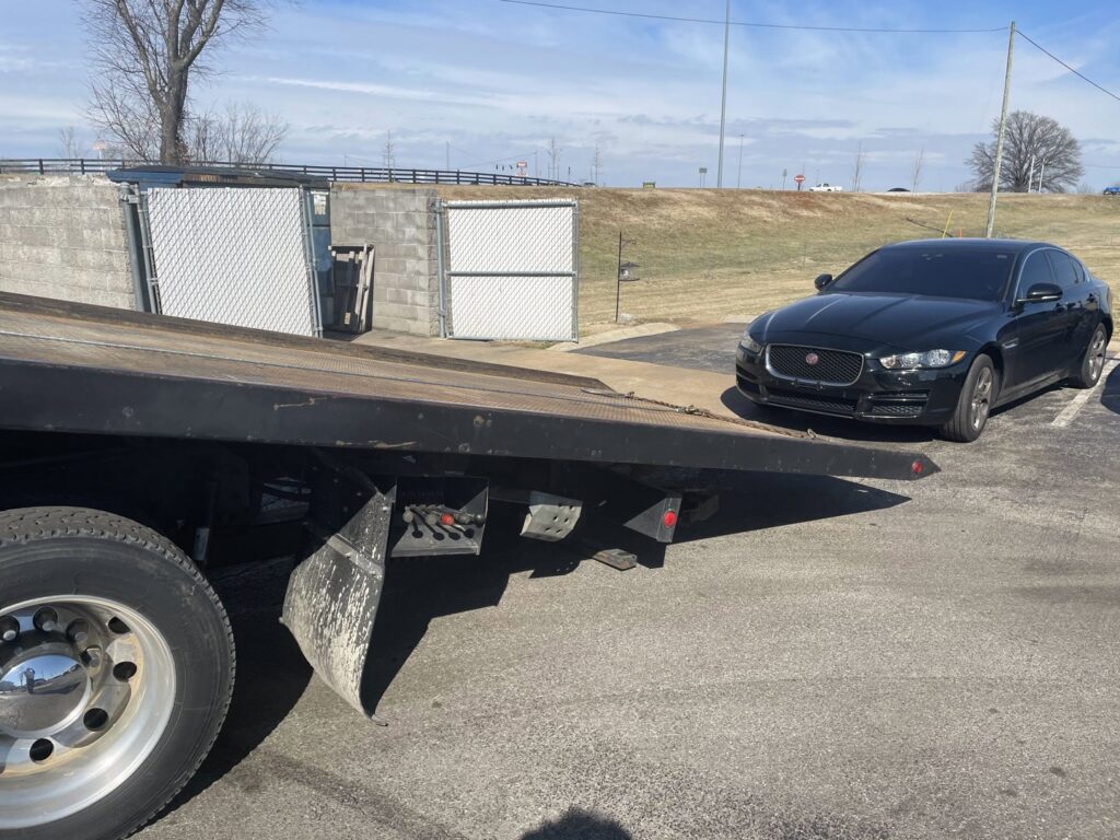A black Jaguar sedan being loaded onto a flatbed tow truck from Wilkerson's Towing & Automotive LLC in Bowling Green, KY.