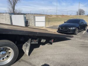 A black Jaguar sedan being loaded onto a flatbed tow truck from Wilkerson's Towing & Automotive LLC in Bowling Green, KY.