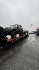 A black Jeep Wrangler being transported on a flatbed trailer by 82Hauling & More LLC in St. Louis, MO