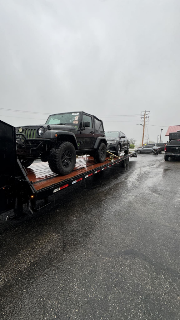 A black Jeep Wrangler being transported on a flatbed trailer by 82Hauling & More LLC in St. Louis, MO