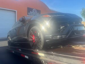 A black Lamborghini Urus being transported on a flatbed tow truck by 247 Towing in San Antonio, TX.