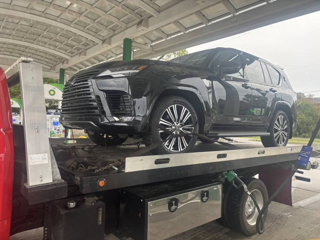 A black Lexus SUV being transported on a flatbed tow truck by Quiñones Towing in Cleveland, OH.