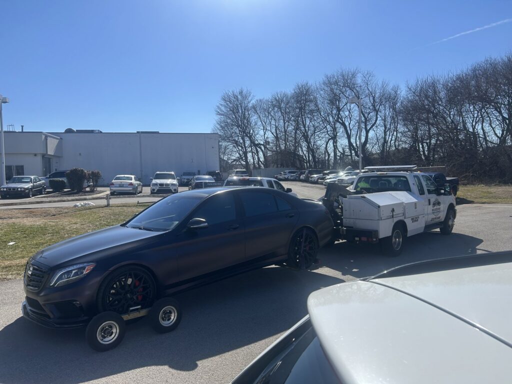 A black Mercedes-Benz sedan on a tow dolly, being towed by Wilkerson's Towing & Automotive LLC in Bowling Green, KY.