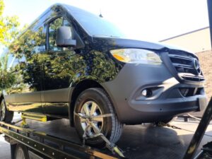A black Mercedes Sprinter van secured on a flatbed tow truck from Pro-Tech Wrecker Service in Decatur, AL.
