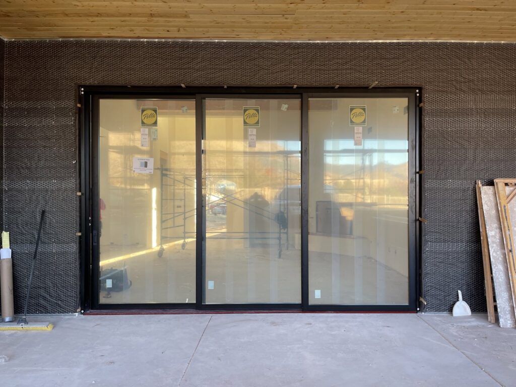A sleek black modern garage door with four top windows, installed by Door Man LLC in Albuquerque, NM.