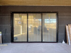 A sleek black modern garage door with four top windows, installed by Door Man LLC in Albuquerque, NM.