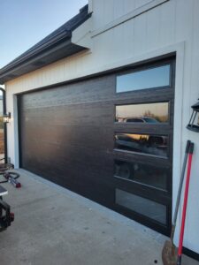 A black modern garage door with vertical windows installed on a new home by ABC Garage Doors KC in Kansas City, KS.