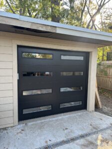 A sleek black modern garage door with horizontal windows installed on a shed by ABC Garage Doors KC in Kansas City, KS.