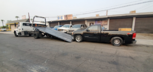 A black pickup truck being loaded onto a flatbed tow truck by Rojo's Towing in Phoenix, AZ.