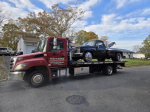 A black pickup truck being towed on a flatbed truck by Riggleman Towing in Moorefield, WV.