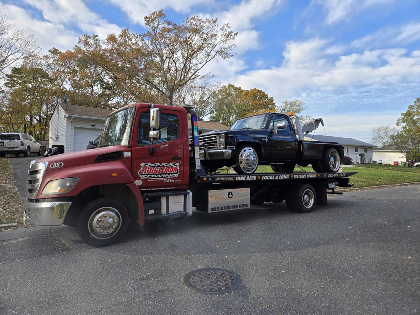 A black pickup truck being towed on a flatbed truck by Riggleman Towing in Moorefield, WV.