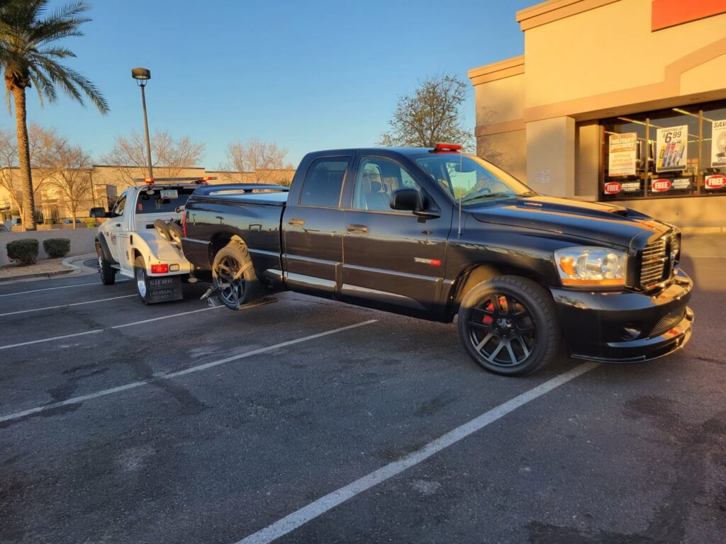 A black pickup truck with a missing wheel being towed by Caliber Towing in Phoenix, AZ.