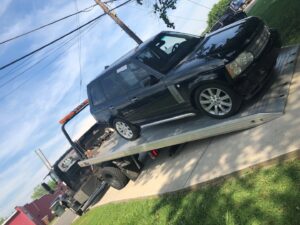 A black Range Rover SUV being transported on a flatbed tow truck by J & G Towing, LLC in Greensboro, NC.