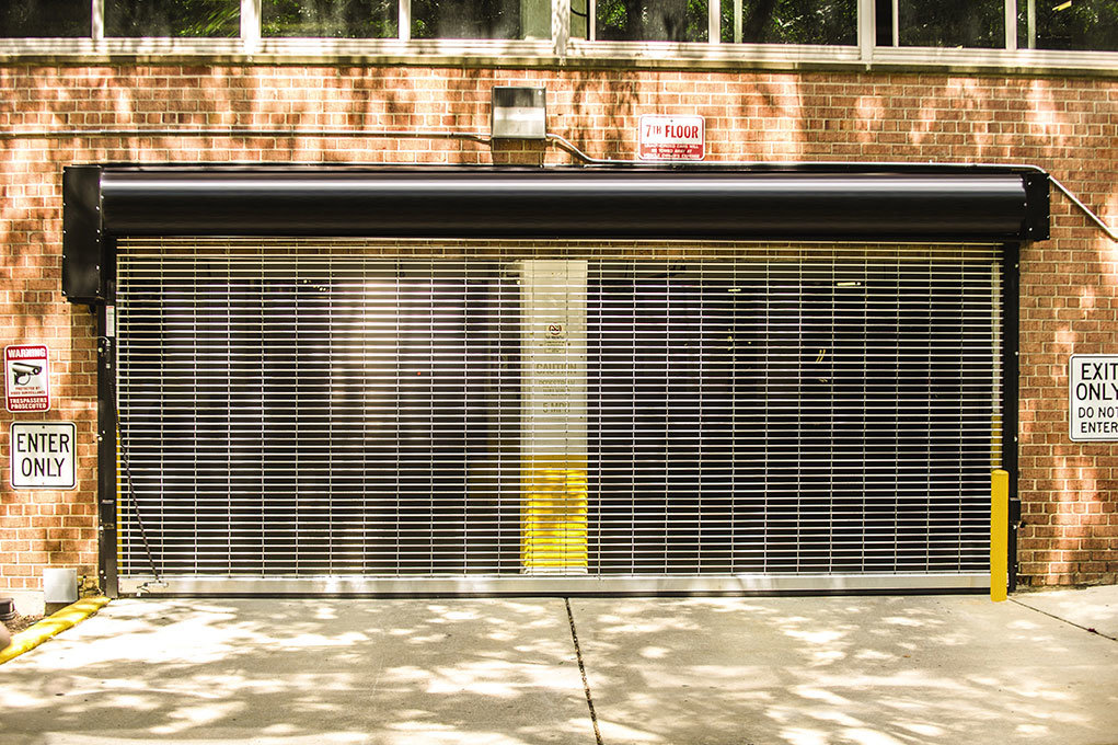 A black rolling grille garage door installed at a parking garage entrance by Wayne Dalton Sales & Service of Quad Cities in Davenport, IA.
